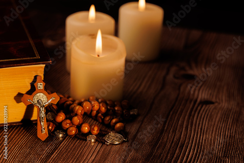 Obraz na plátně Bible with purple cover and white candles on a dark wooden background for illustrating christianity and spiritual devotion today