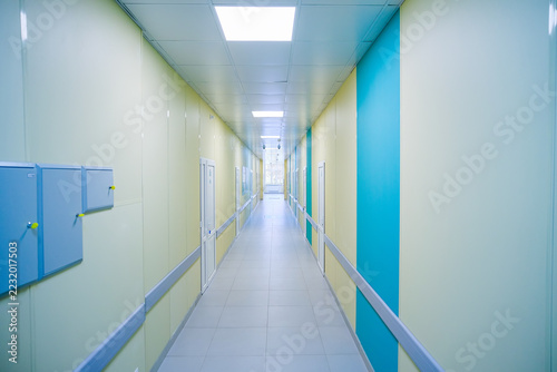 Fotografie Long, brightly lit hospital corridor with yellow walls and blue accents