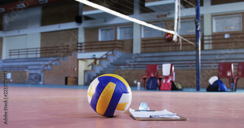 A volleyball rests on a gym floor, signaling a break in the game