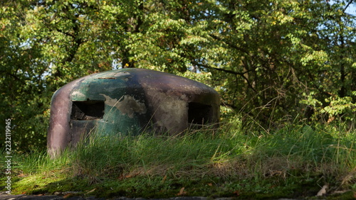 Fotografie Steel armored observation cupola of World War II military bunker buried in grassy hill with forest background