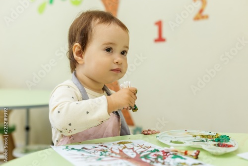 Attentive Toddler with Paint-Covered Hands Next to Finished Autumn Tree Painting, Copy Space