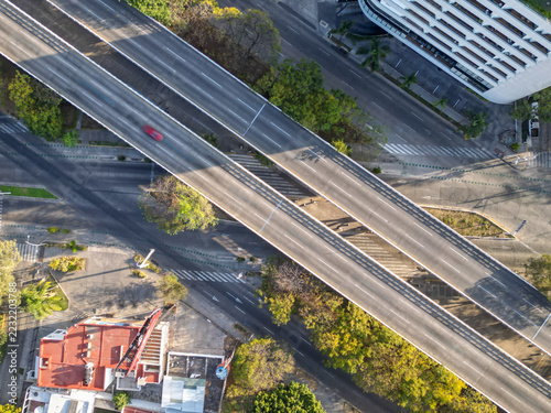 Fotografie High angle drone shot capturing a highway intersection in Guadalajara, Mexico, with a modern architectural building