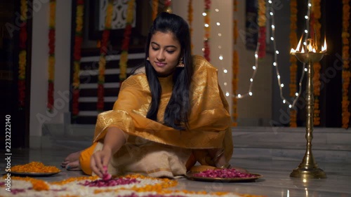 Diwali decoration - Gorgeous Indian girl / female making flower rangoli. 