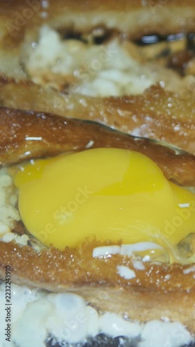 White bread with a central hole is filled with a raw egg and fried in a pan of sunflower oil. This close-up captures an indulgent, oil-heavy breakfast associated with excessive calorie intake.

