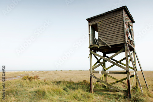 Wooden watchtower overlooks a dry coastal marsh and distant sea