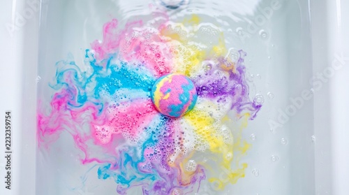 Colorful Bath Bomb Fizzing in a White Bathtub with Pink, Blue, Purple and Yellow Swirls, Top View