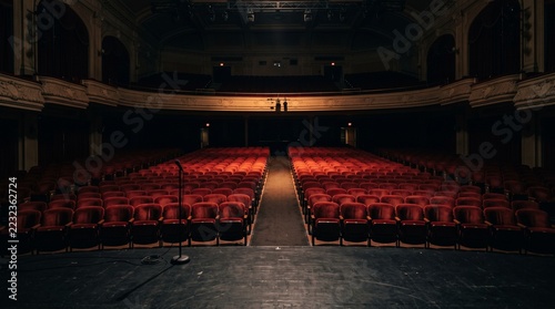Microphone on Stage Facing an Empty Theater Auditorium with Red Seats and Balcony