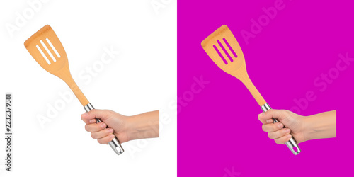 Fotografie A hand holding a bamboo kitchen spatula with a silver handle for cooking food tr