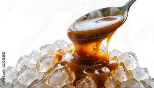 Macro of hot caramel melting over a mound of crushed ice, steam rising as the liquid thickens, isolated on a white background.
