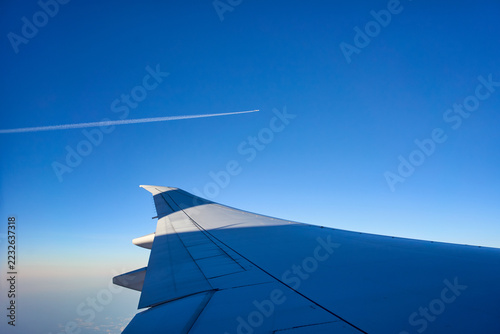Airplane wing view while flying in high blue sky and other airplane fly together.