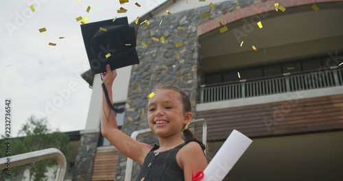 Image of gold confetti over celebrating caucasian schoolgirl throwing mortar board in air