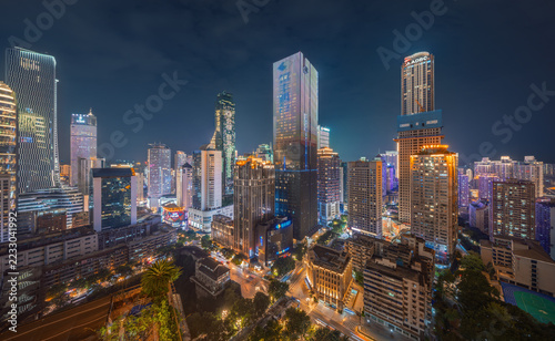 Illuminated skyscrapers rise above dense residential buildings and streets at night in Chongqing, China