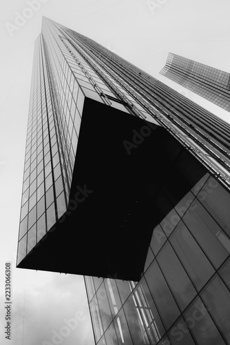 Glass skyscraper viewed from below beside modern office tower. Contemporary urban architecture and business district. Geometric facade and structural design. Black and white architectural