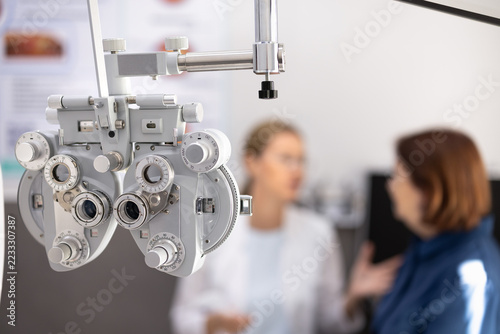 Obraz na plátně Closeup view professional phoropter equipment, patient and eye doctor blurred in background