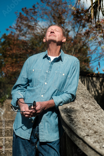 Photography Man relaxing in autumn sunshine beside a stone railing