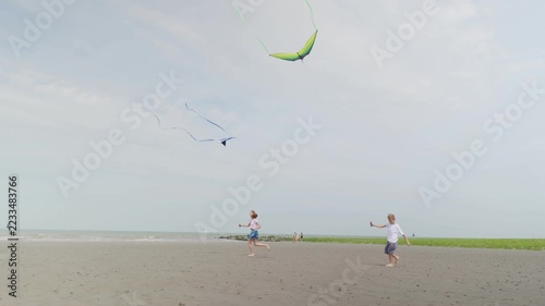 Happy boy and girl running barefoot with kites on a sandy beach children at a seaside resort