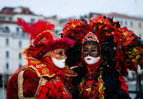Fotografie Venice, Italy - February 12, 2026: Venice Carnival revelers in red masks and fea