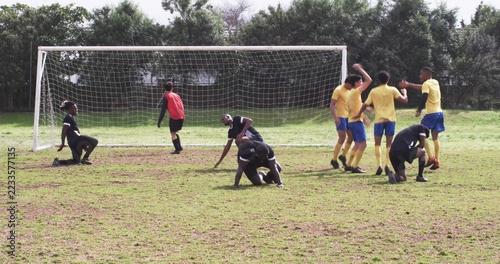 Fotografie Diverse male soccer players forming defensive formation in front of metal goal f