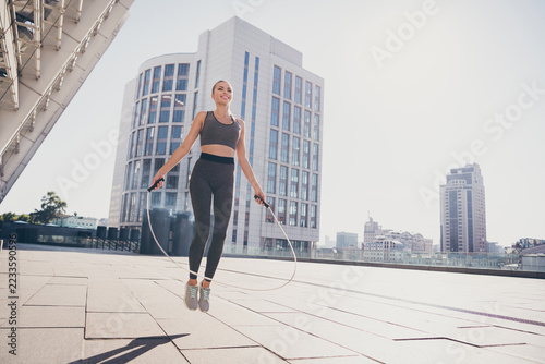 Full length photo of sportive dynamic positive lady jump rope up doing challenge effort outside gym