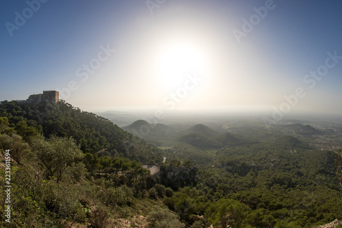 Fotografie Hügellandschaft auf Mallorca im Gegenlicht, bewaldete Berge und Täler im Dunst m