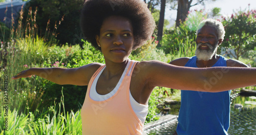 African american senior couple exercising practicing yoga standing in sunny garden