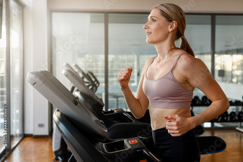 Obraz na plátně Determined woman running on a treadmill at the gym
