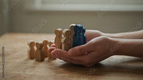 Hands holding blue figurines next to a group of wooden figures on table, created with generative ai.   