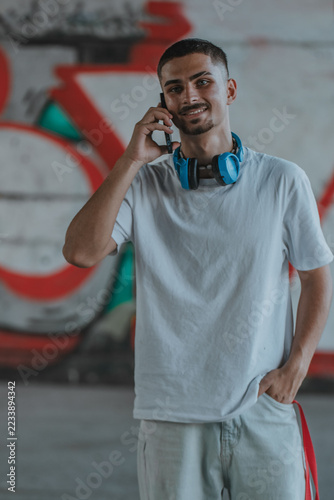 Young person in casual style talking on a mobile phone on an urban street