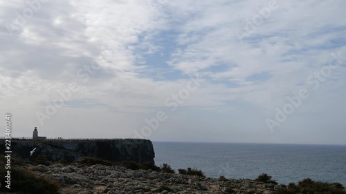 Rocky cliffs in Algarve region of southern Portugal with distant lighthouse