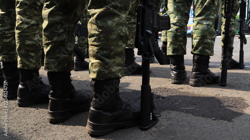 Obraz na plátně Military troops in camouflage and combat boots hold rifles during a formal lineu