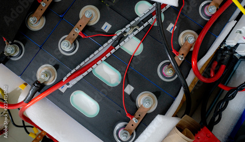 Fotografie Close up of lithium ion NMC battery cells connected with copper busbars and electrical cables inside an EV battery pack, showing high voltage energy storage technology for electric transportation