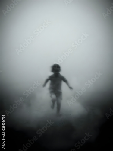 Blurred figure of a child running out of the fog