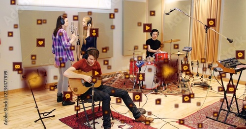 Strumming guitarist in rust shirt, headphones playing acoustic guitar in studio with drums and mics