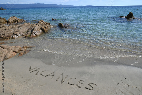 Vacances écrit en français sur le sable d'une plage d'Ajaccio
