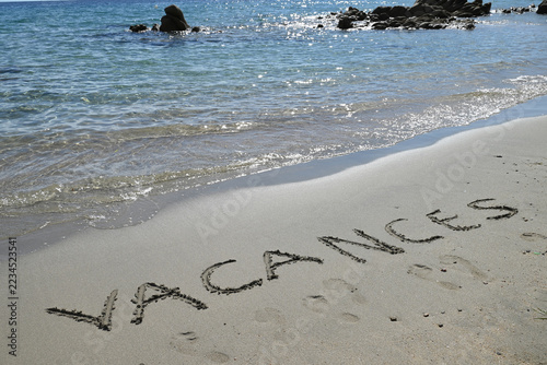 Vacances écrit en français sur le sable d'une plage d'Ajaccio