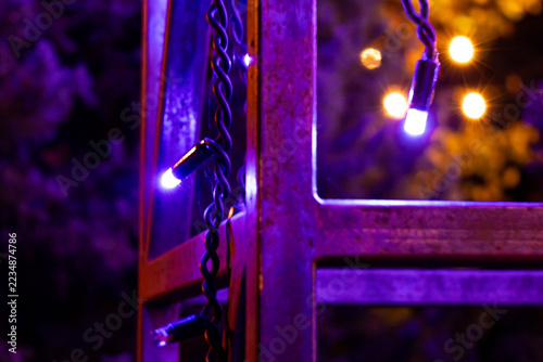 Purple string lights hang from a metal frame outdoors at night