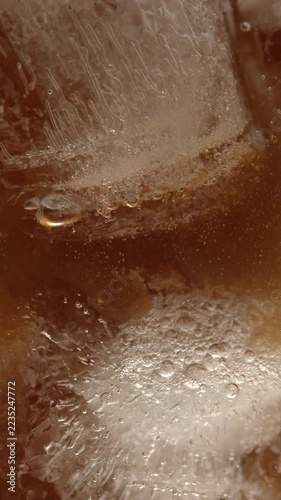 The process of preparing a summer coffee cocktail: a serving of Americano is slowly poured in a thin stream into a glass containing mineral water and ice.