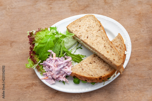 Sandwich with egg and coleslaw on white plate indoors