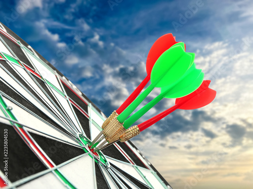 Fotografie Darts in bullseye of dartboard against sky at sunrise