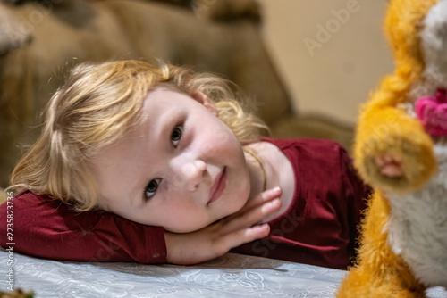 Child lying beside a stuffed toy