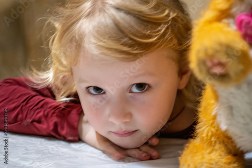 Child lying beside a stuffed toy