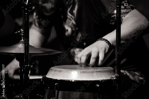 Obraz na plátně Black and white close-up of percussionist playing conga drum with fingers beside a cymbal on a dark jazz stage
