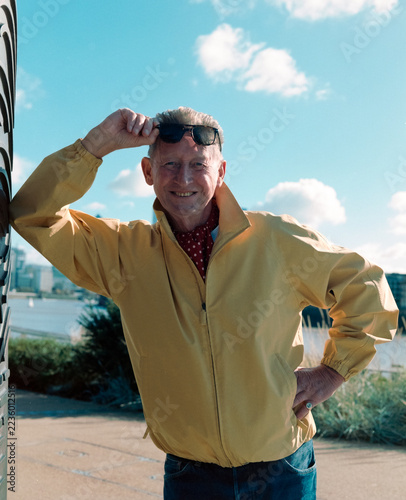 Photography Smiling older man in yellow jacket adjusting sunglasses outdoors