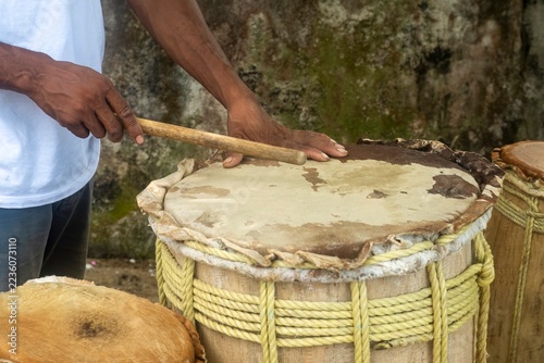 Musician playing traditional wooden afro-descendant drum, performance.