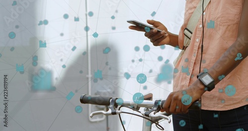 Standing beside bicycle holding smartphone, resting hand on handlebar, network icons, copy space