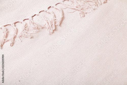Textile product with long fringe lies on white fabric