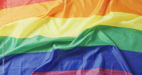 Image of creased rainbow flag lying on white background