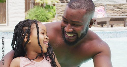 Portrait of happy african american father and daughter having fun in swimming pool