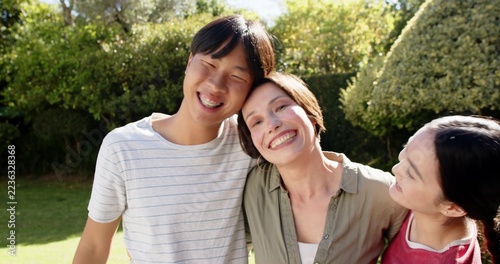 Fotografie Asian family standing together in backyard garden leaning heads close and smilin