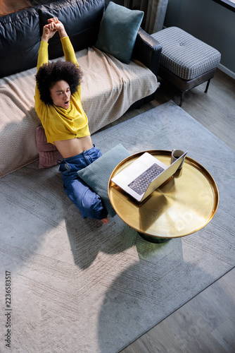 Woman relaxes in the living room with a laptop in front of her.